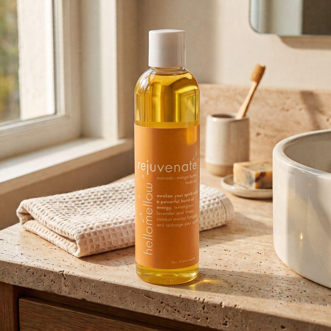 rejuvenate body oil on a warm bathroom counter beside a folded towel