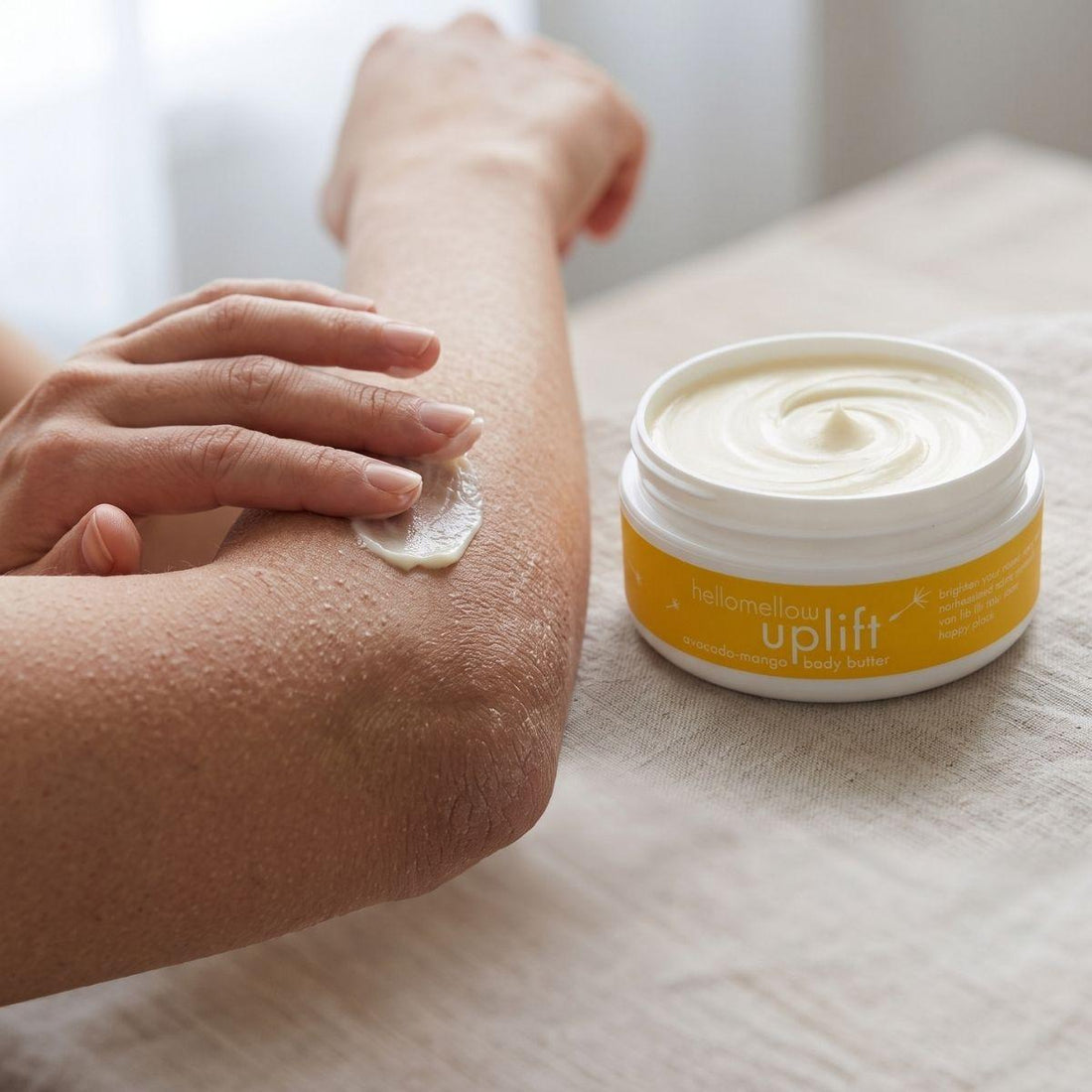 hands applying uplift body butter to a dry elbow for targeted moisture