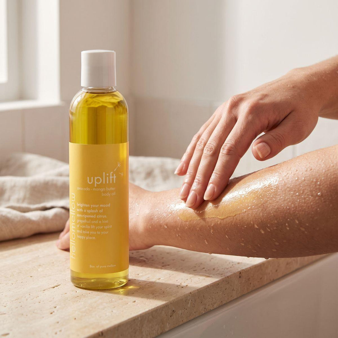 hands smoothing uplift body oil onto damp skin after a shower