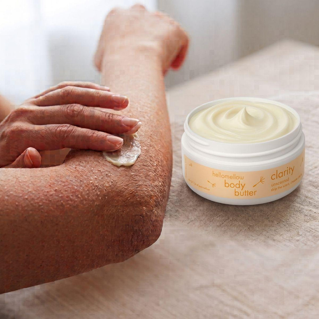 hands applying clarity body butter to a dry elbow for targeted moisture