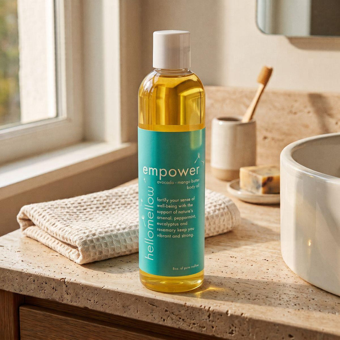 empower body oil on a warm bathroom counter beside a folded towel