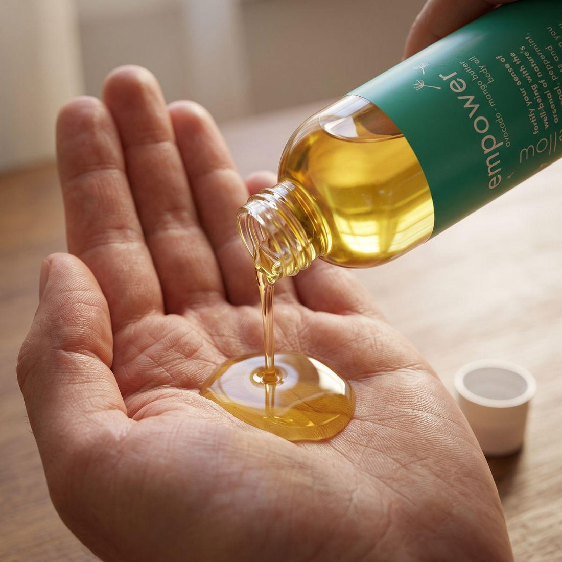 empower body oil pouring into an open palm with the bottle nearby