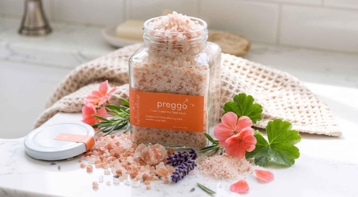 glass jar of mineral foot soak with pink and white salts, lavender and geranium in a bright bathroom.