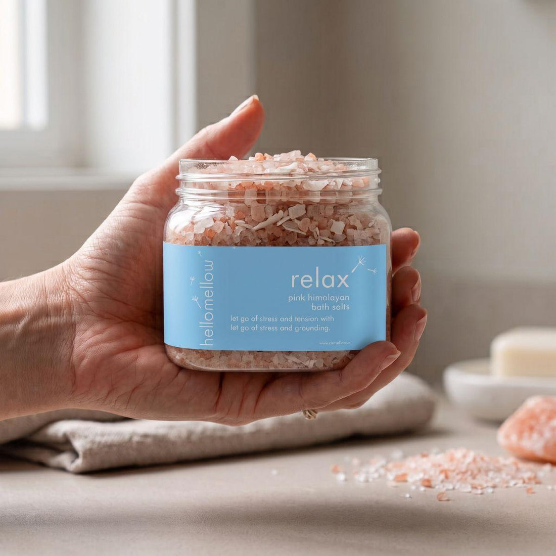 adult hand holding the relaxbath salts jar with the label facing forward