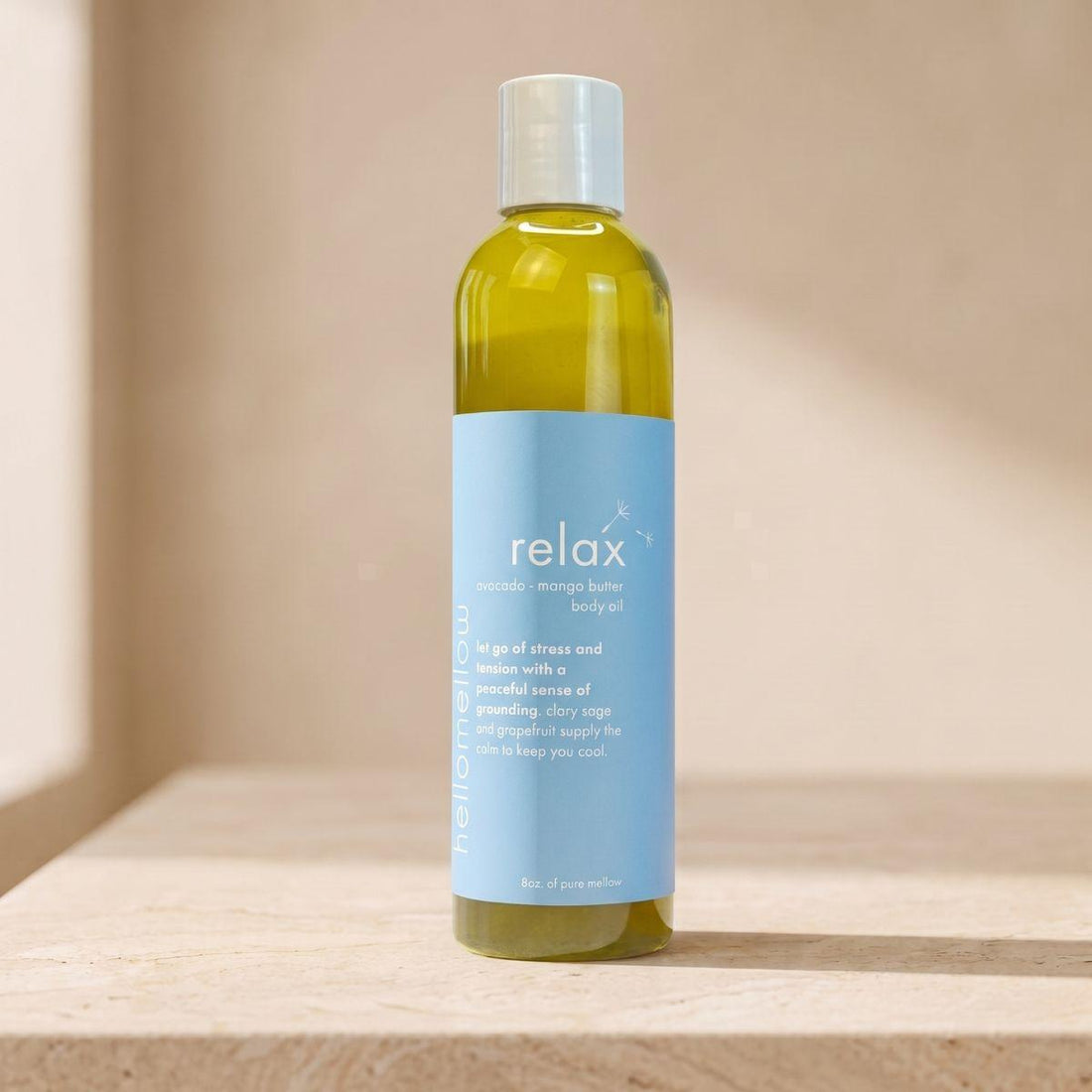 relax body oil bottle standing front-facing on a warm neutral surface