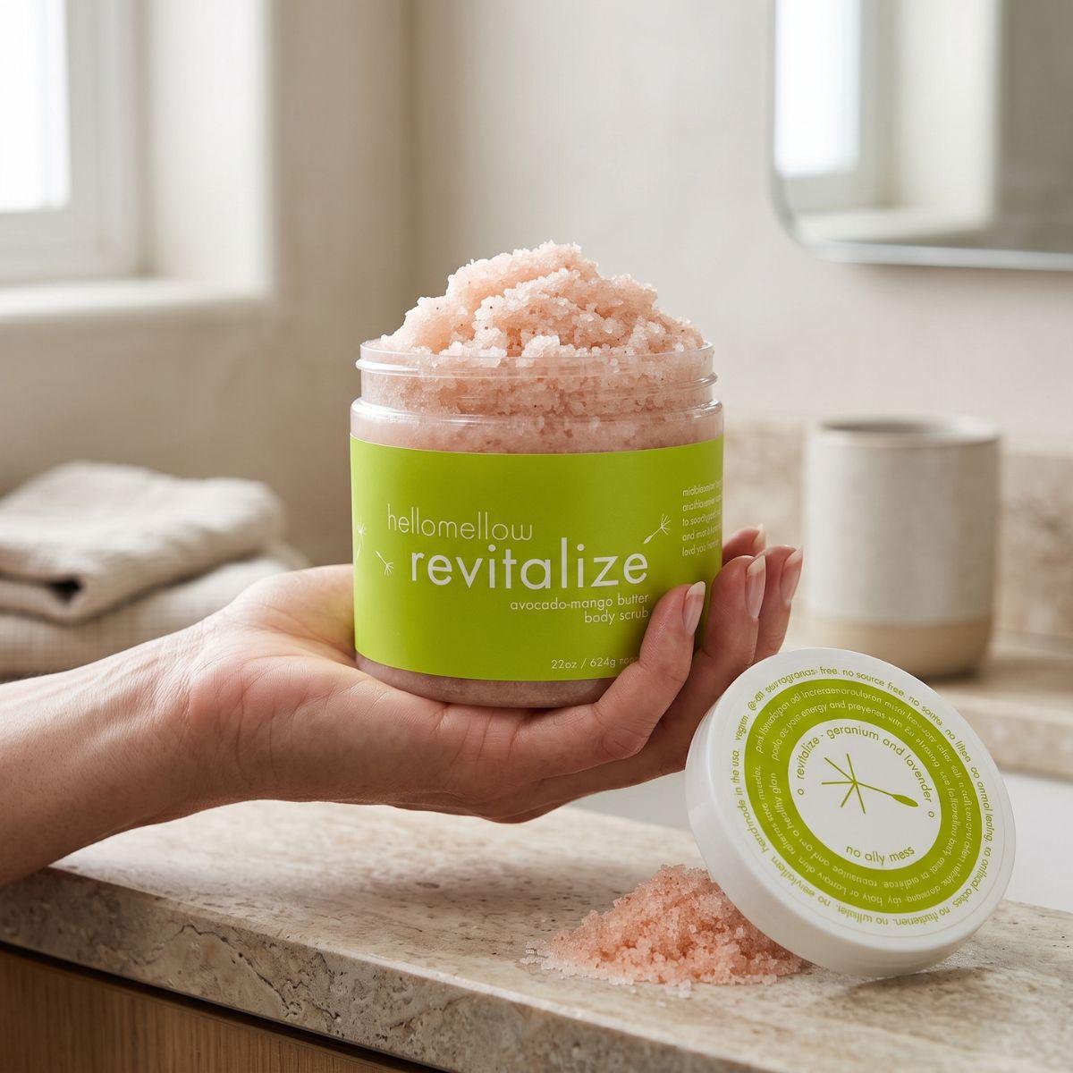 adult hand holding the revitalize body scrub jar with the label facing forward