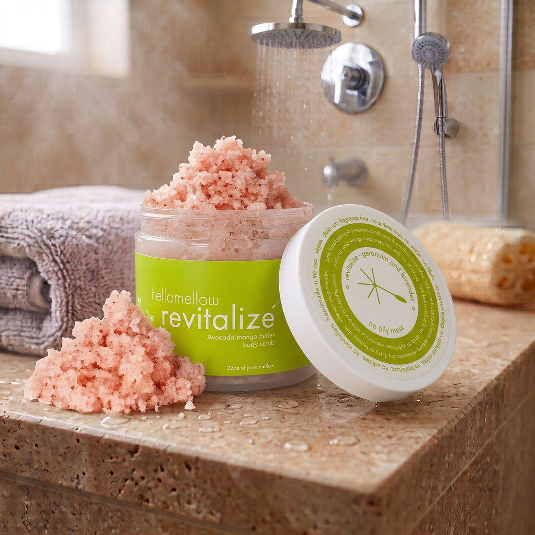 revitalize body scrub on a shower ledge beside a folded towel