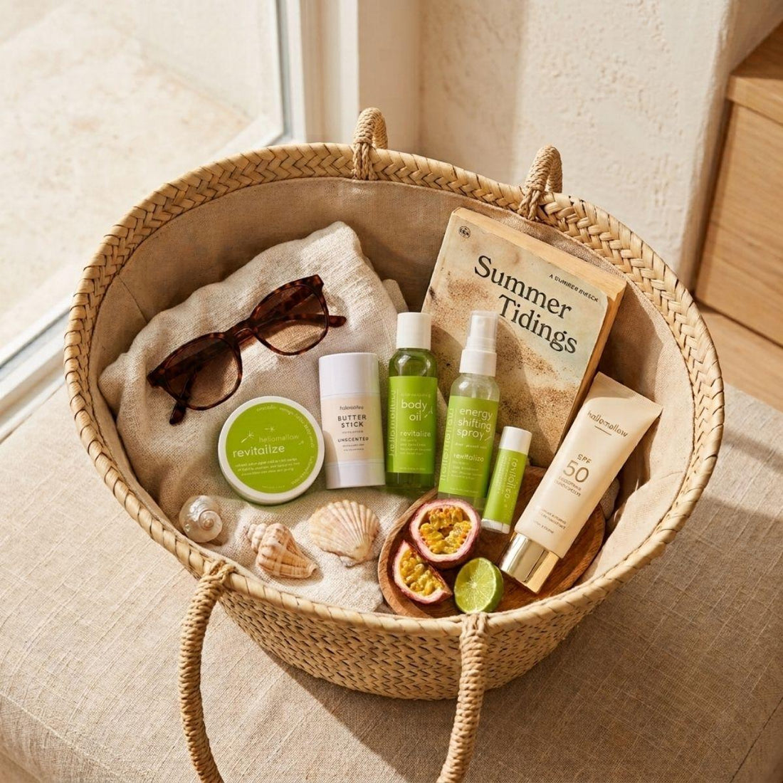 revitalize deluxe vacay vibe in a cozy travel basket mini body scrub, one unscented body butter stick, mini body oil, mini energy shifting spray, lip butter pictured with a book sunglasses and sunscreen