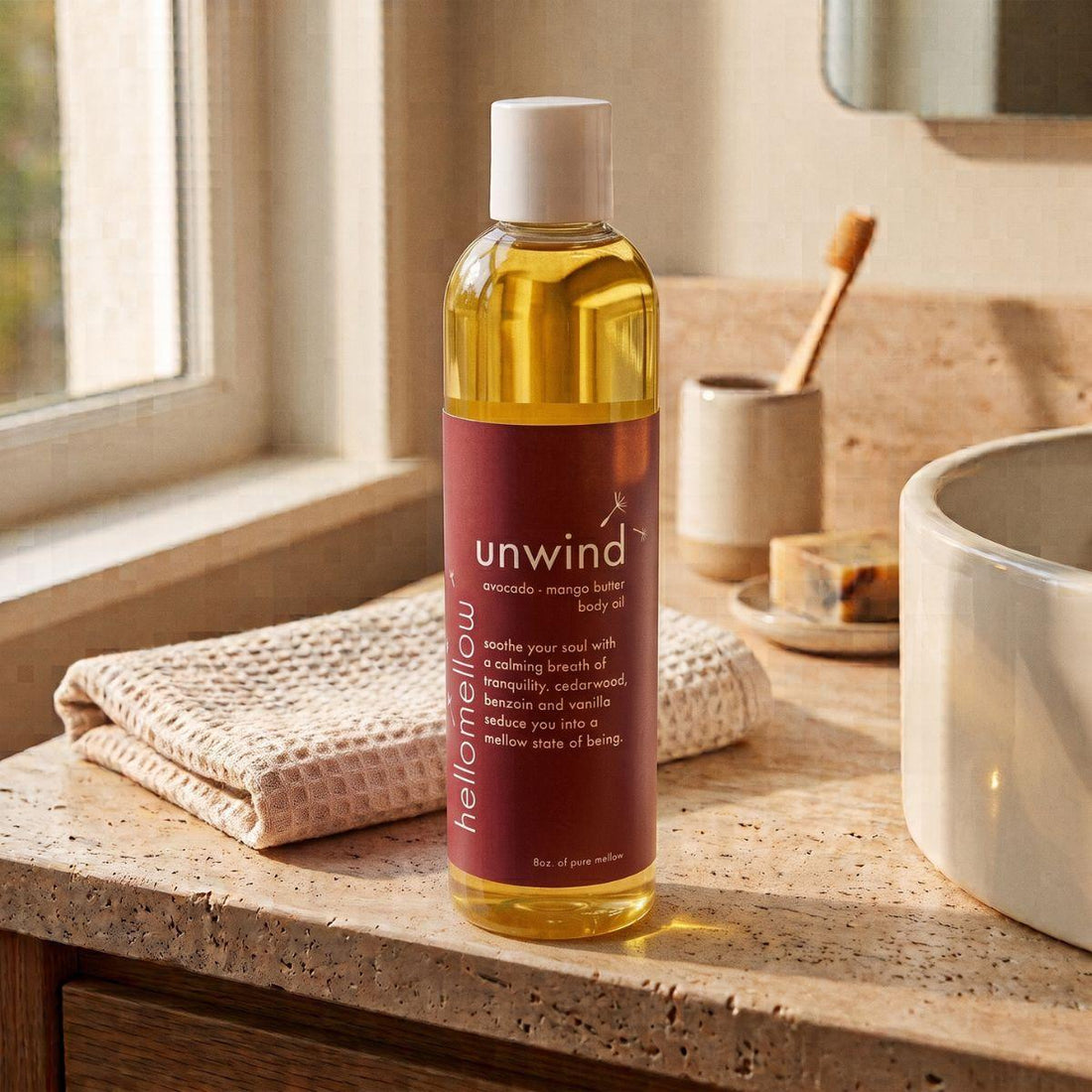 unwind body oil on a warm bathroom counter beside a folded towel