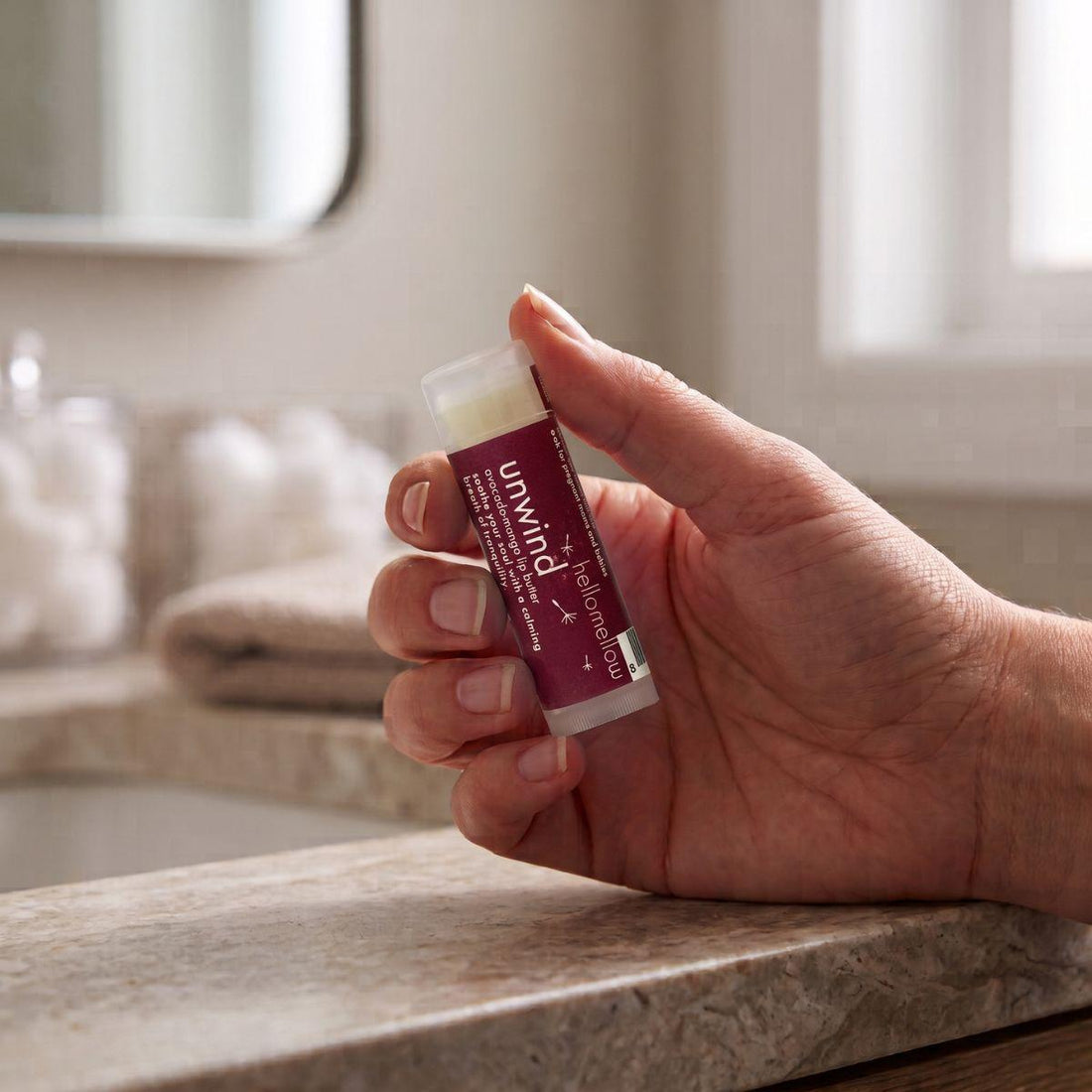 adult hand holding the uniwind lip butter to show its everyday size