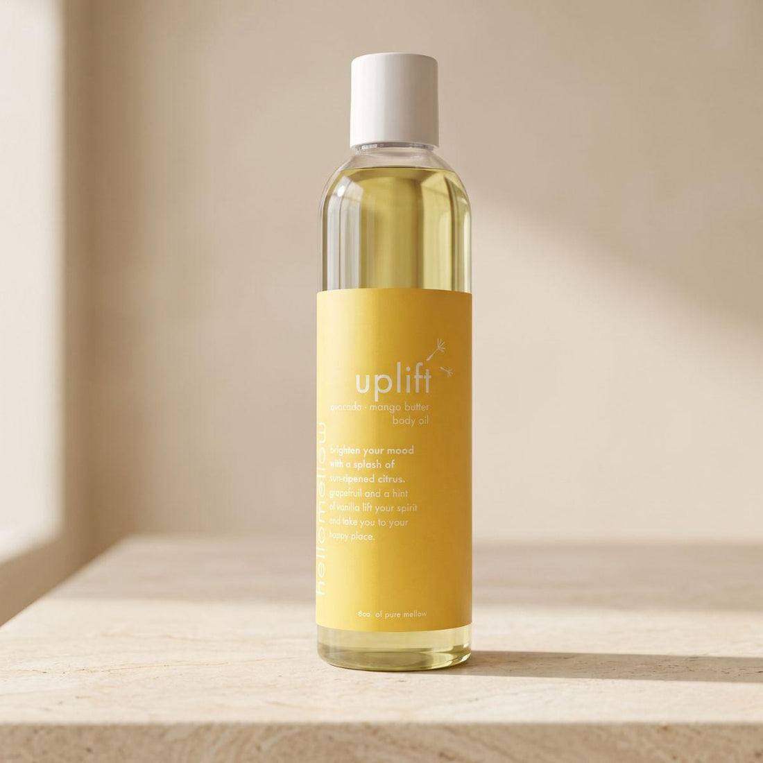 	 uplift body oil bottle standing front-facing on a warm neutral surface