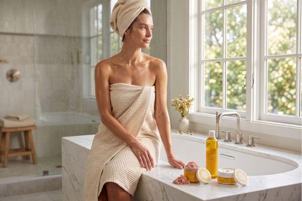 woman in a towel beside uplift complete mellow method products in a bright bathroom.