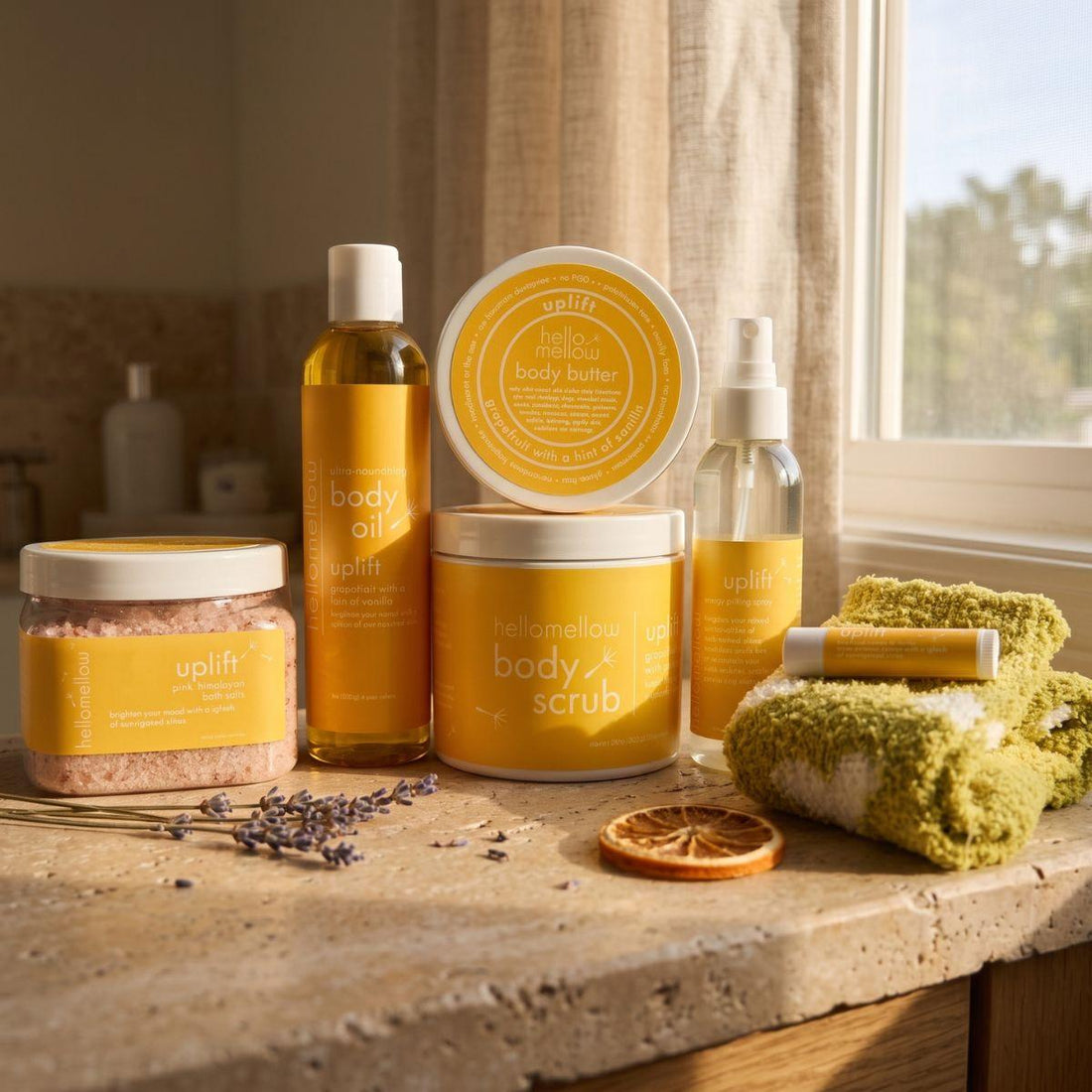 uplift body scrub, body oil, and current butter products grouped together on a warm bathroom counter