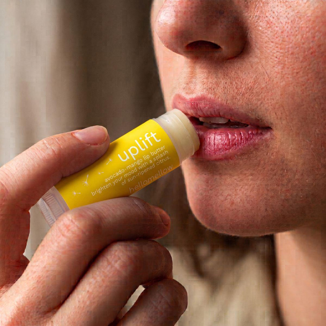 uplift lip butter being applied naturally to lips in soft daylight